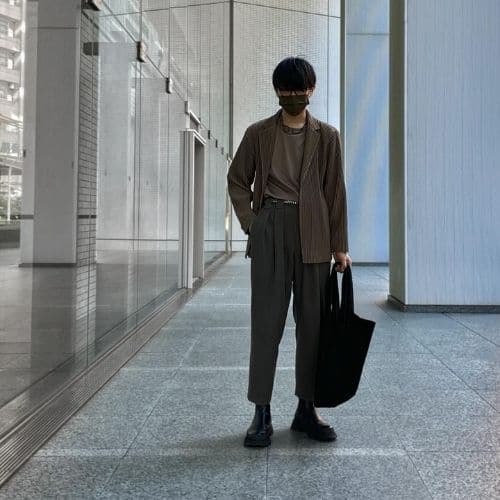 Outfit minimalista de hombre, con saco, pantalones plisados y bolsa tote