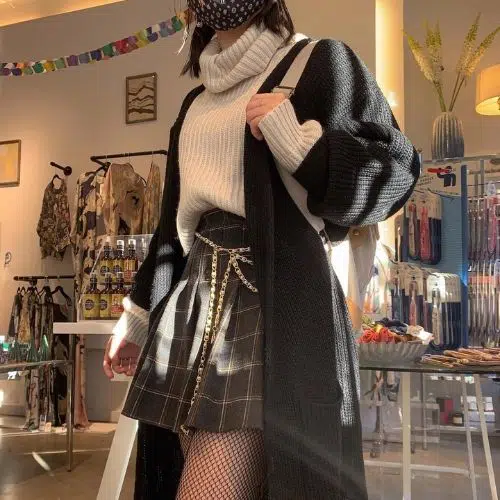 Outfit de estilo dark academia con falda tableada, abrigo y suéter tejido