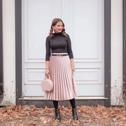 Outfit con falda rosa plisada, blusa negra y bolsa rosa
